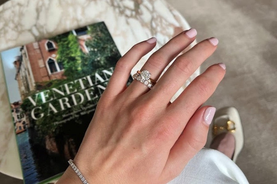 Diamond engagement ring on hand above marble table at Orsini