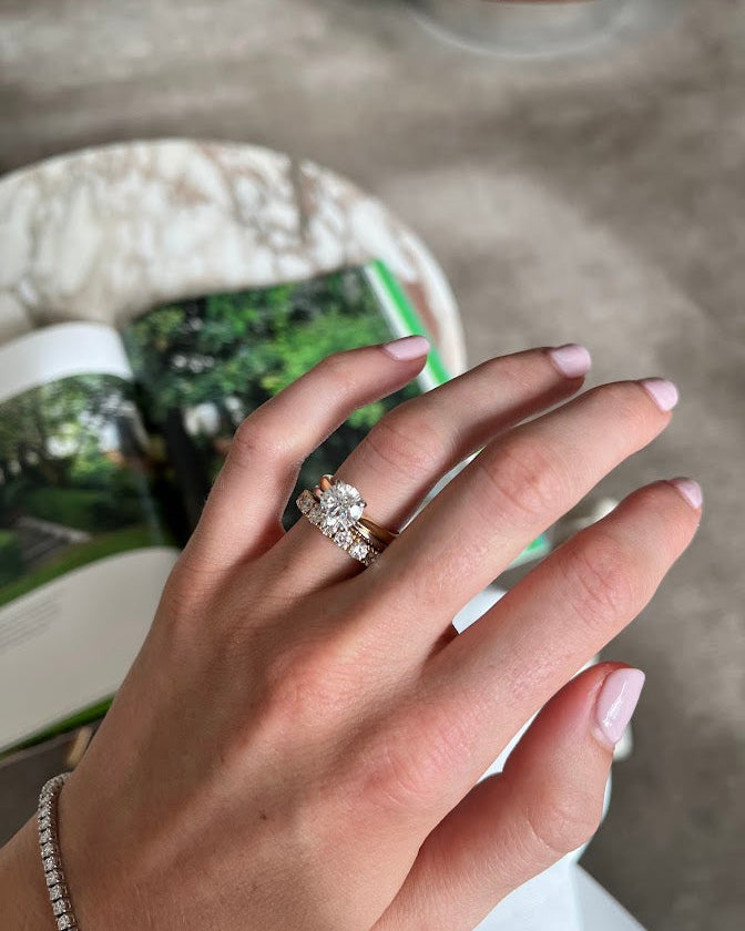Hand wearing a diamond engagement ring with a blurred background