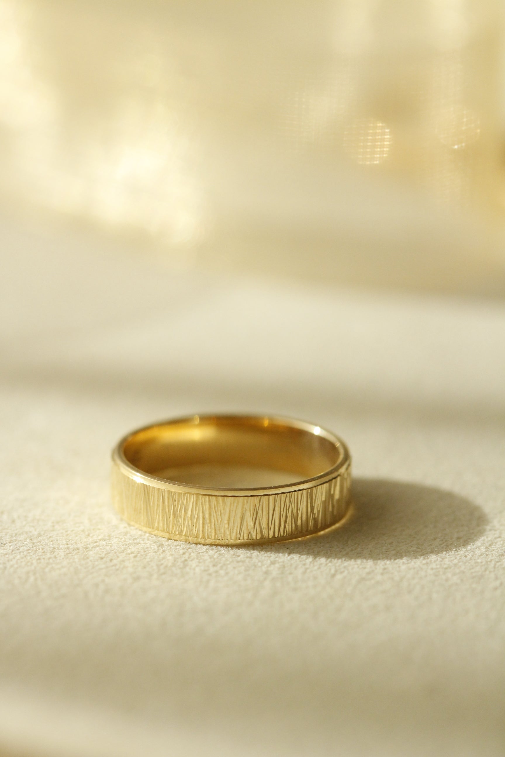 Yellow gold men's wedding ring design on white fabric