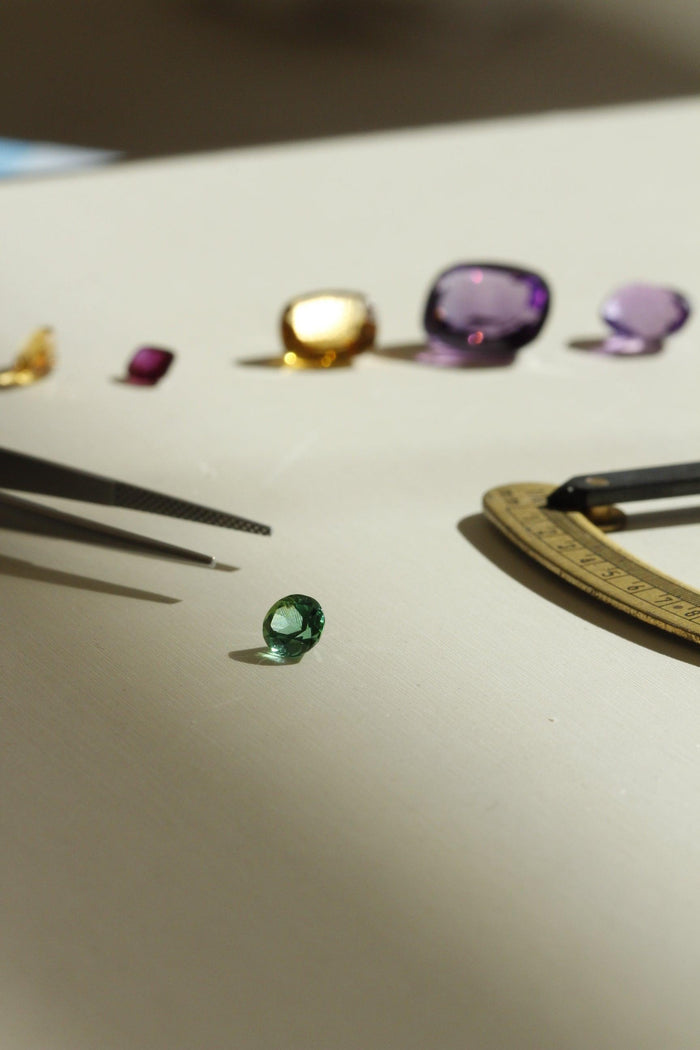 Emerald stone hand selected with jewellery tools and other gemstones in background