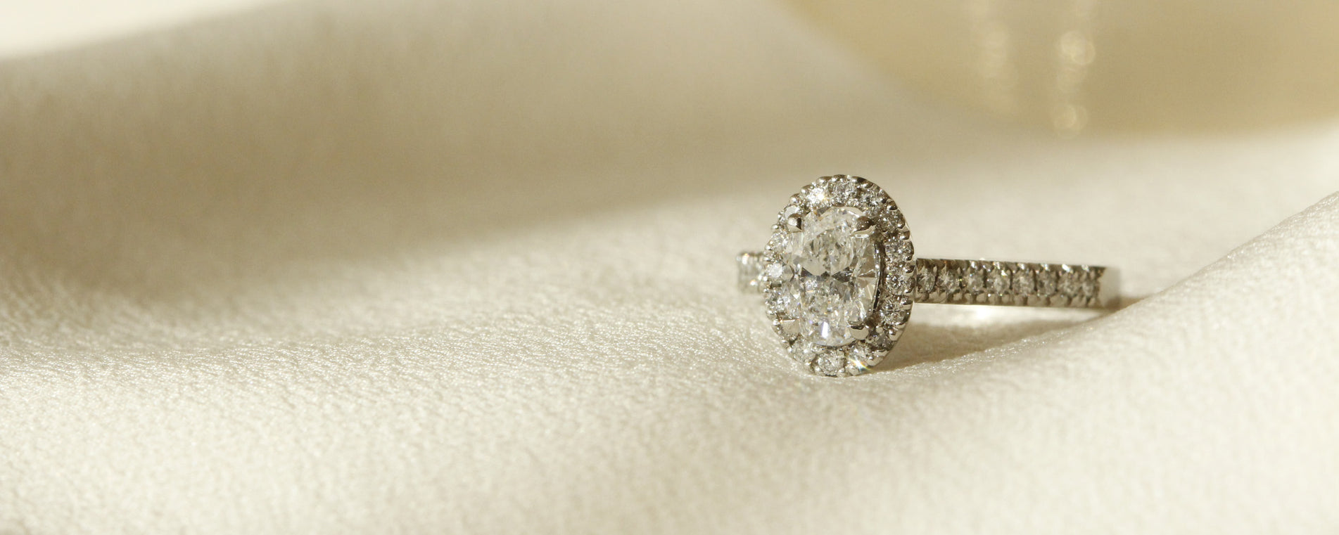Oval diamond with diamond halo and diamonds on hand white gold engagement ring Le Fenice Oval setting by Orsini Fine Jewellery horizontal cropped image
