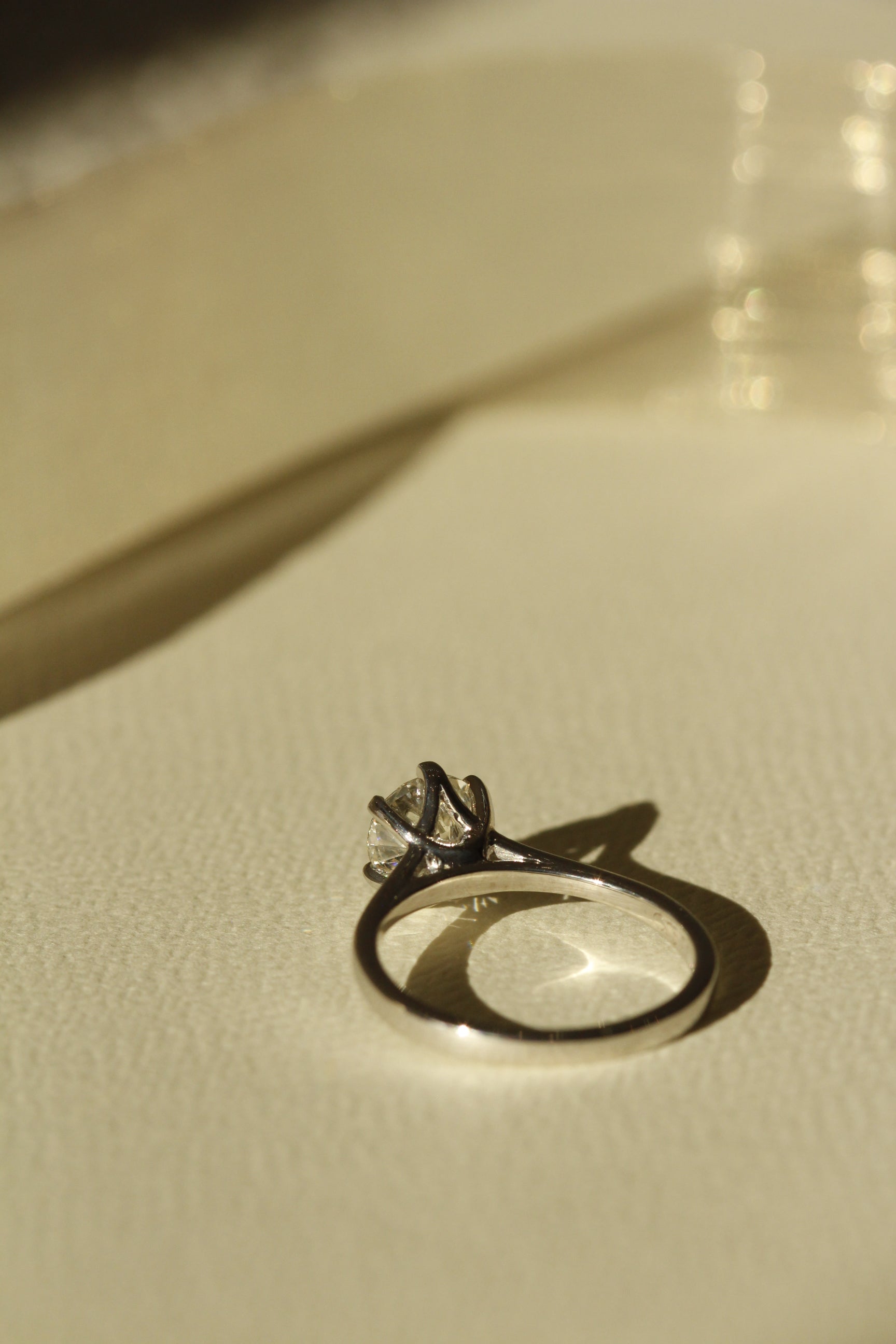 Ducale ring setting centre diamond and gold band taken of behind ring and gold ribbon in background