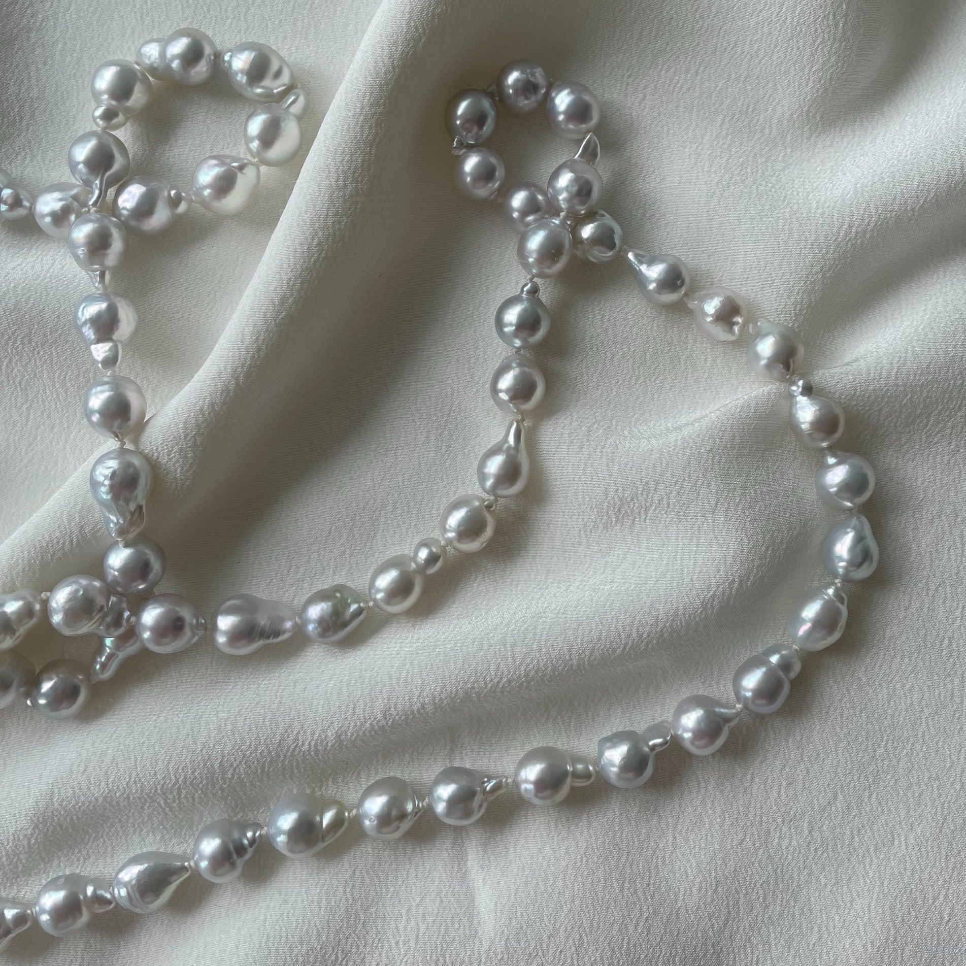 Pearl necklace by Hulchi Belluni taken on silk fabric used as an image for a jewellery repair page