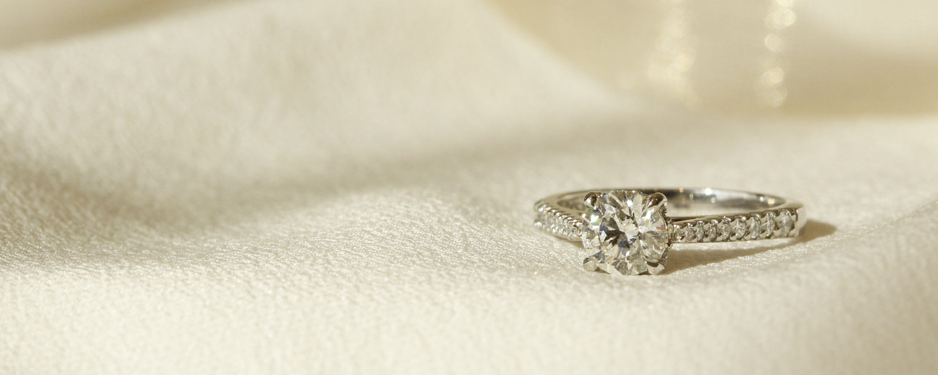 Solitaire diamond engagement ring with gradual diamonds on band set in 18k white gold horizontal image of Bernini setting by Orsini Fine Jewellery 
