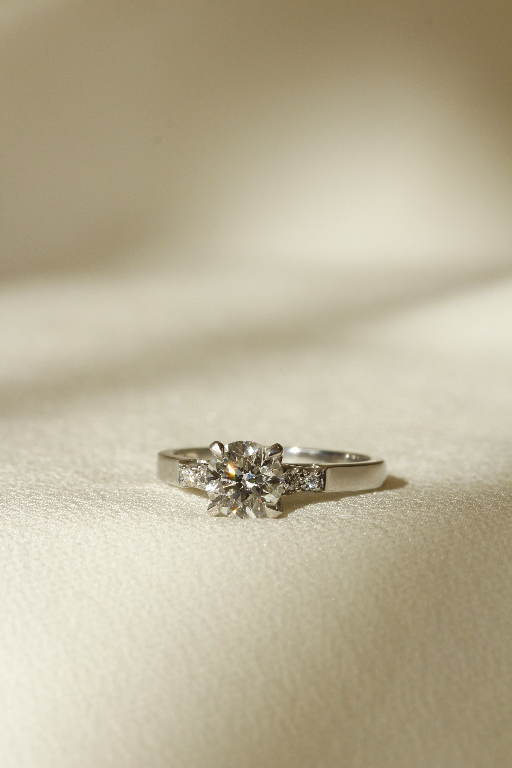Round diamond with diamonds on band engagement ring Galvani design image of ring on white silk cloth 