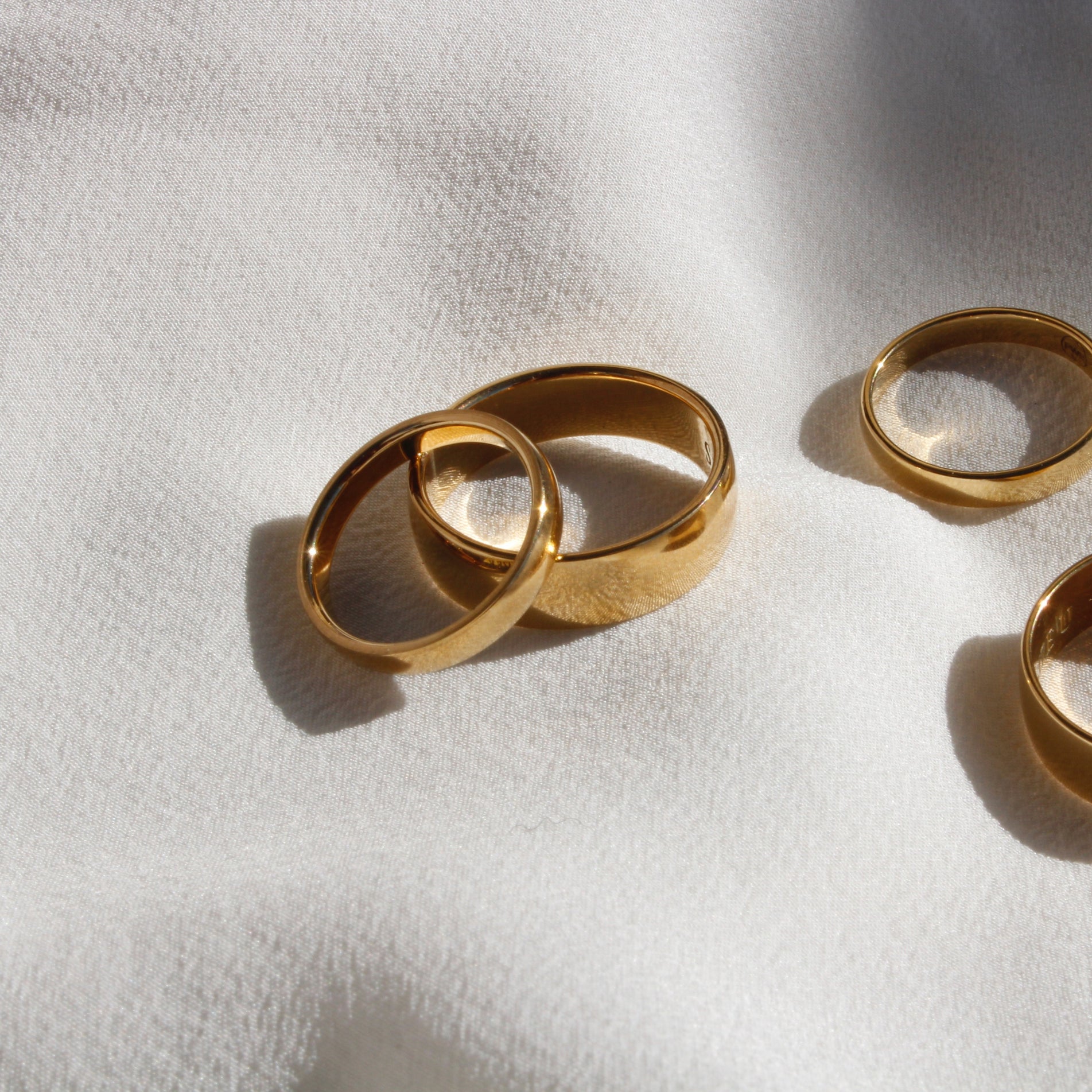 Four Classic Wedding Rings Yellow Gold on a white Fabric