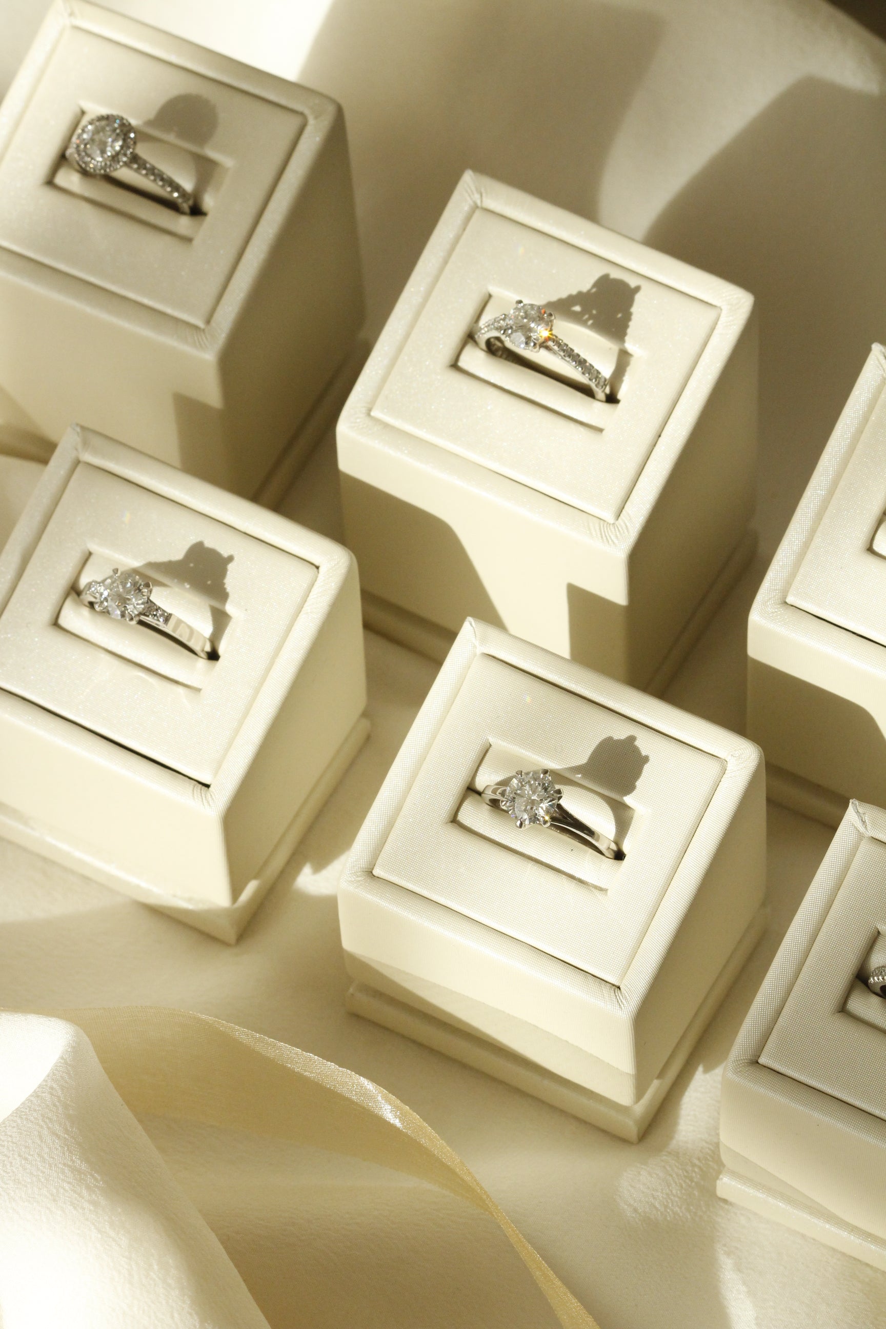 Multiple Engagement Rings in white gold with diamonds sitting in their jewellery stands 