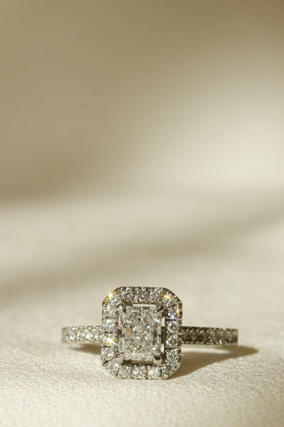 Radiant diamond engagement ring with diamond halo vertical image on fabric Le Fenice Radiant setting 