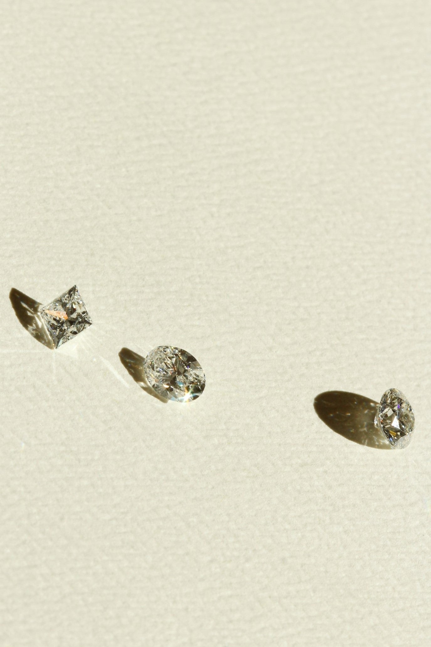 Three Diamonds Oval Diamond Round Diamond and Princess Cut Diamonds on a peice of Card